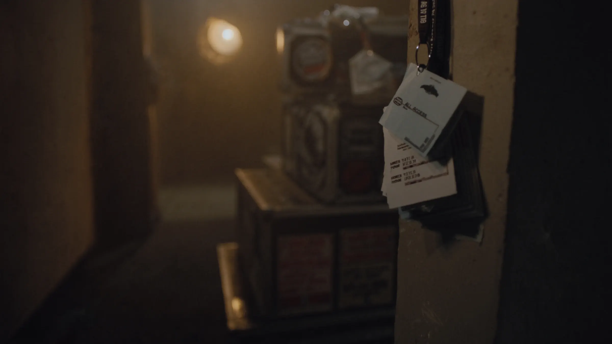 All-access laminates hanging backstage beside stacked flight cases, lit by a single tungsten lamp